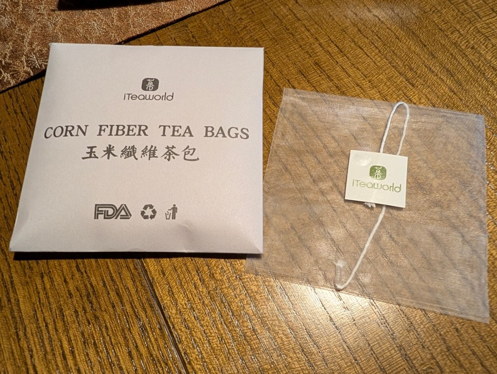 A packaging of corn fiber tea bags from iTeaworld, showing a label with the text 'CORN FIBER TEA BAGS' in English and Chinese, alongside a transparent tea bag.