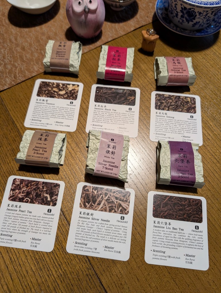An assortment of tea samples from iTeaworld's Jasmine Tea Discovery box, including beautifully packaged loose-leaf teas and educational cards detailing each variety.